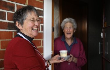 A Meals on Wheels Volunteer delivering a hot meal to a recipient