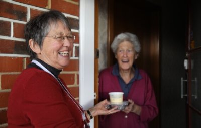 A Meals on Wheels Volunteer delivering a hot meal to a recipient